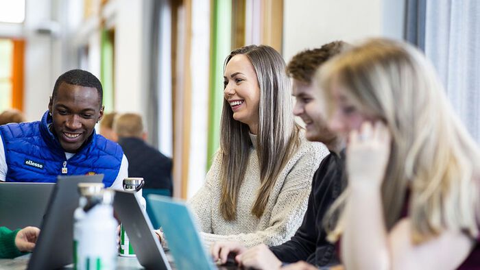 Smilende studenter på biblioteket. 
