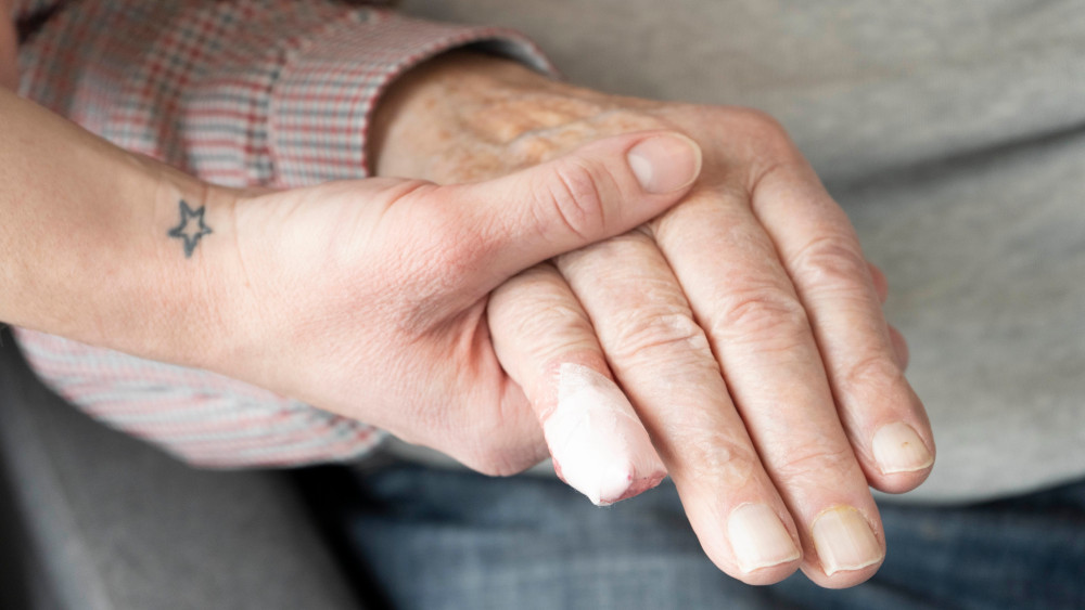 A young looking hand holding the hand of an elderly person. 