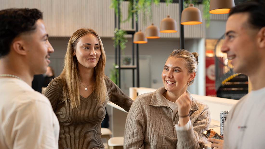 Blide studenter på Elverum som smiler til hverandre. 