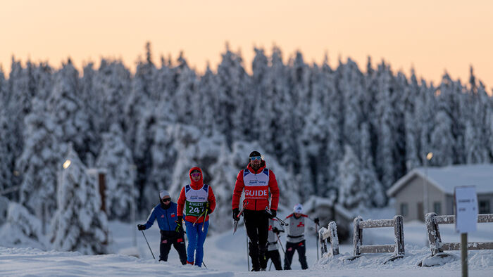 Menn i skiklær ute i et snødekt terreng. 