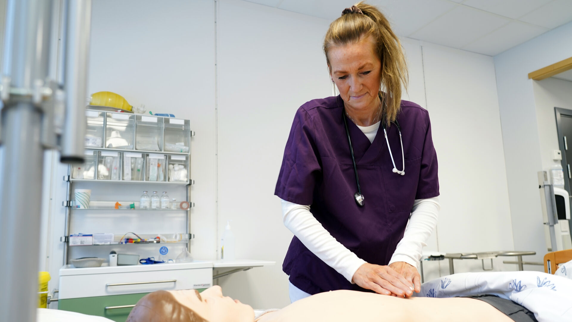 Kvinnelig sykepleiestudenter som jobber på en dokke.