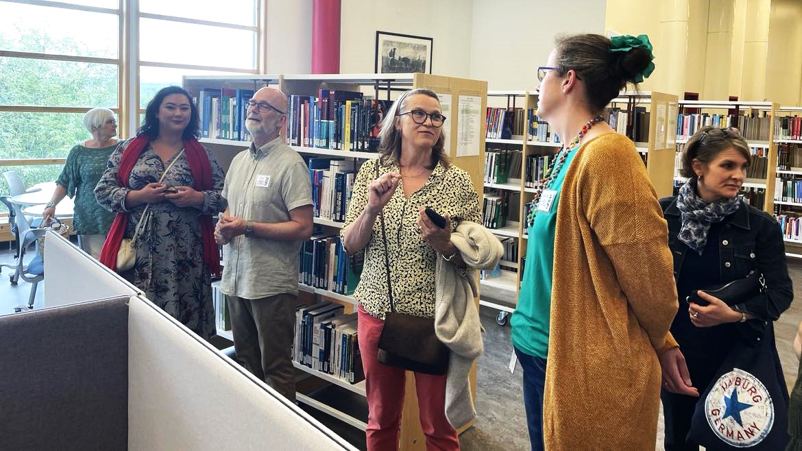 6 personer står i biblioteket på campus Rena. 