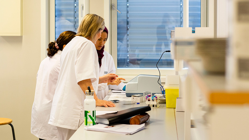 Tre personer i et av høgskolens laboratorier, iført hvite frakker