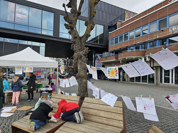 Viser barn som skaper en avisforsiden på et stort ark, på bakgrunn henger flere avisforsider som allerede er laget