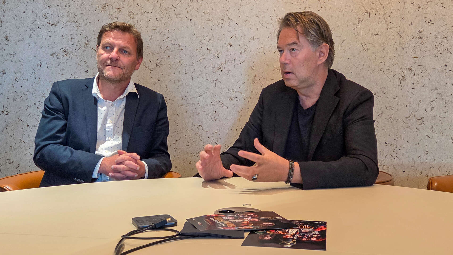 To menn sitter ved et bord og diskuterer