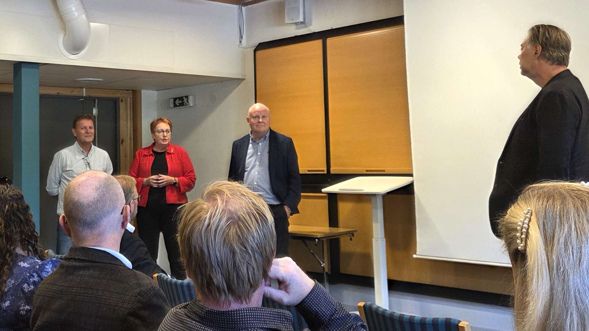 Fire personer står foran en sittende gruppe i et møterom. En kvinne i rød jakke (ordfører Elin Såheim Bjørkli) ser ut til å snakke, mens tre menn står ved siden av henne.