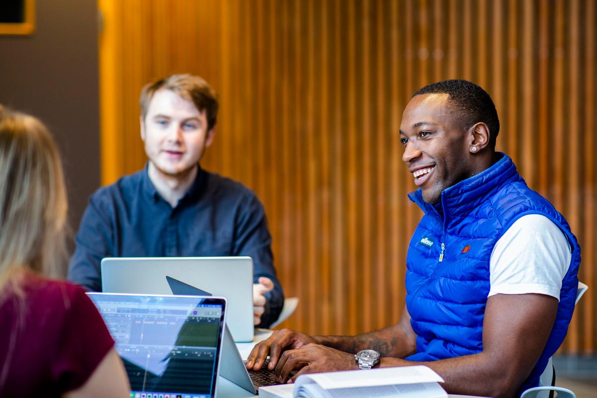 Studenter i samtale foran pc'n