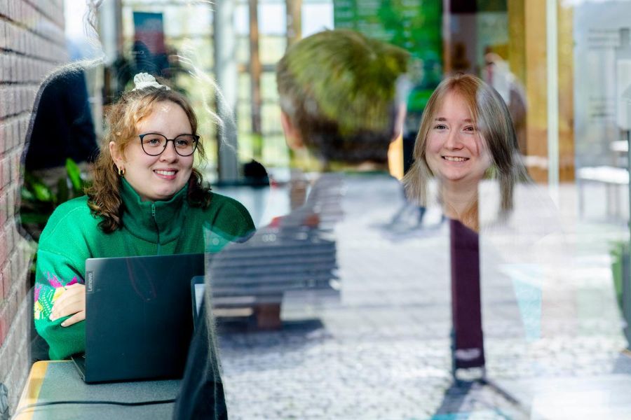 Studenter i samtale med en foreleser sett igjennom et vindu.