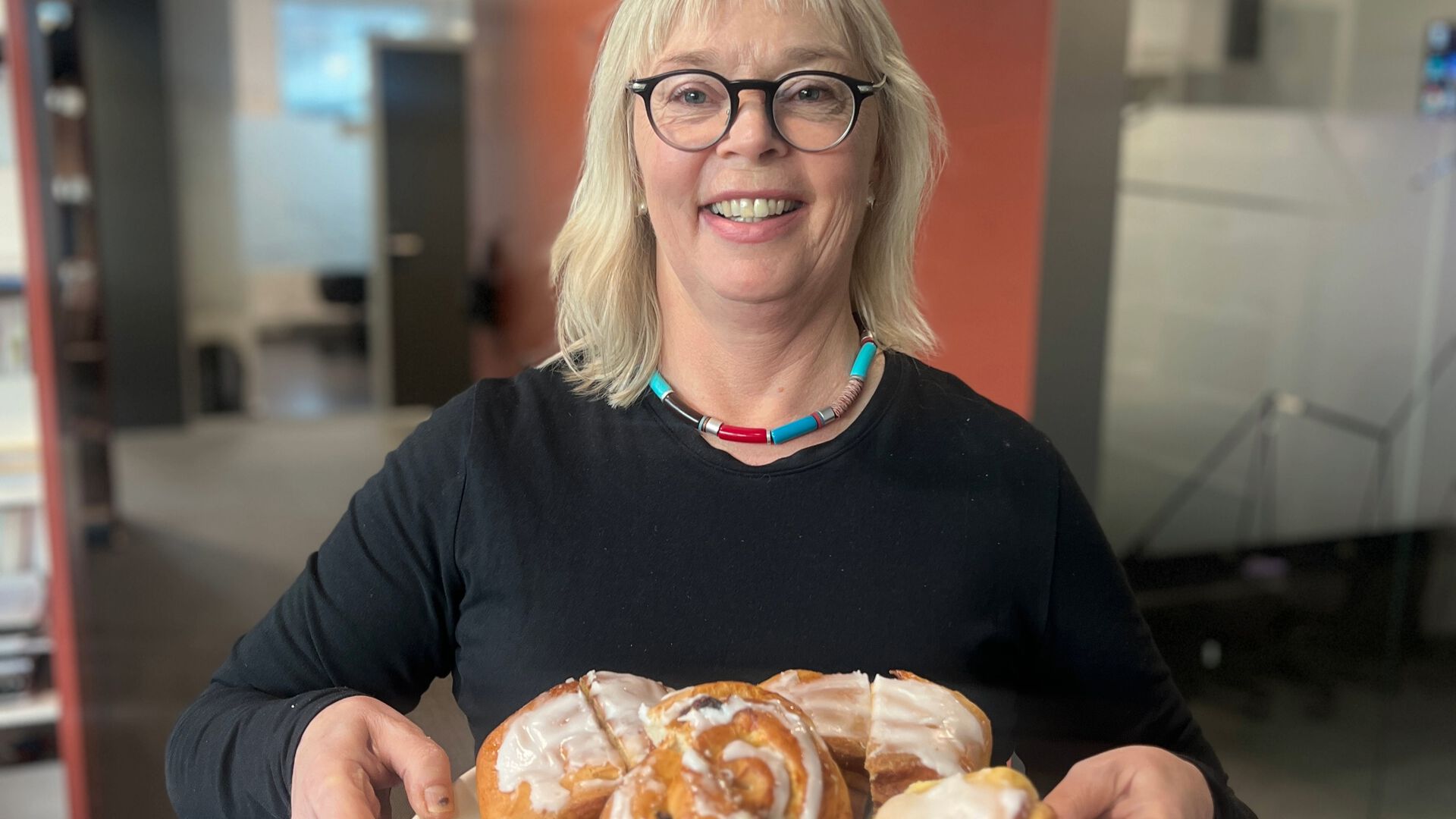 Smiling lady 60 years old offers cinnamon buns 
