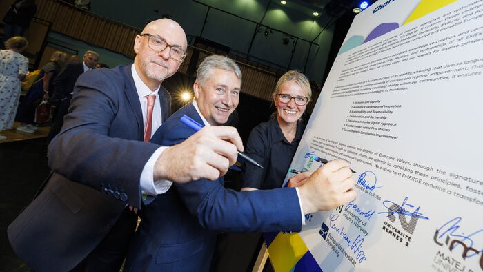 The three are smiling as they are holding markers on the board