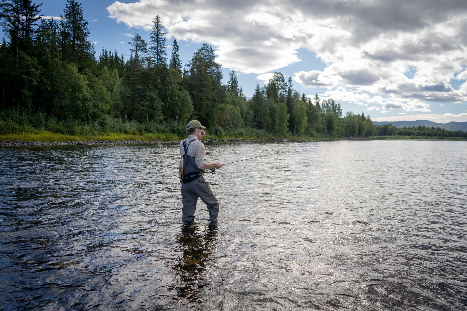 Male student standing in the river fishing.