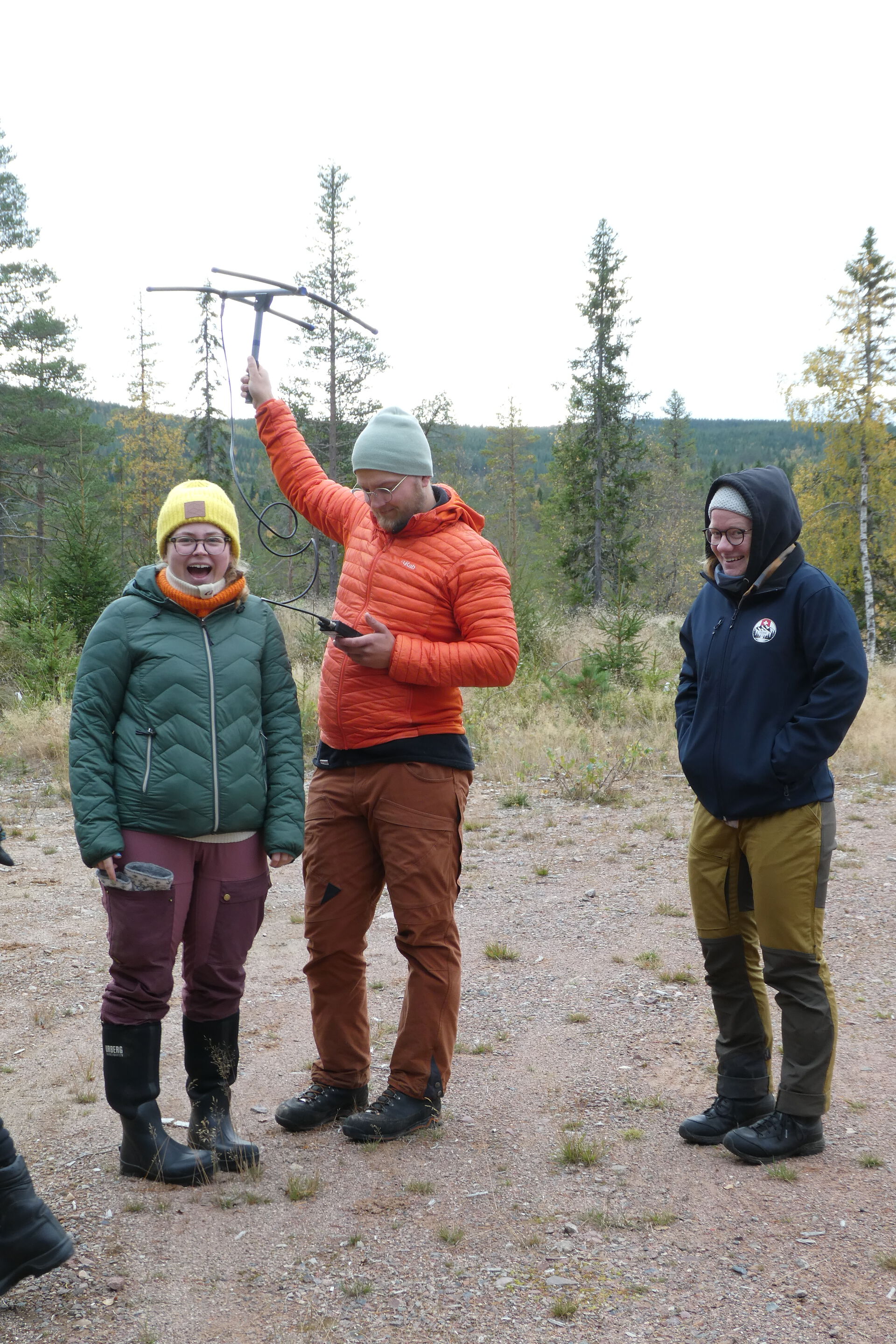 Three people gathered outside, where one of them are holding a transmitter