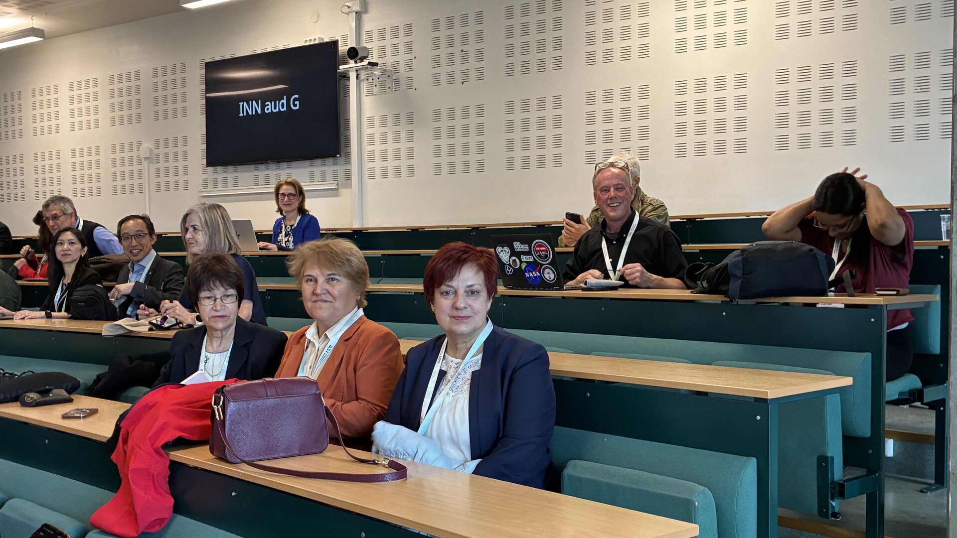 Smiling conference participants sitting in an auditorium.