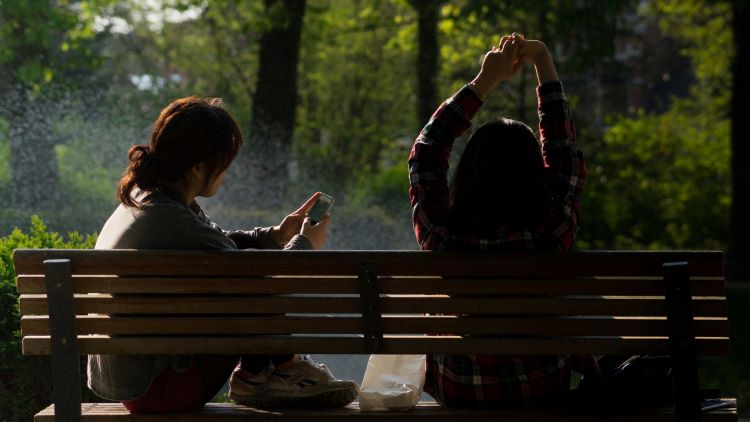 Two persons are sitting on a park bench