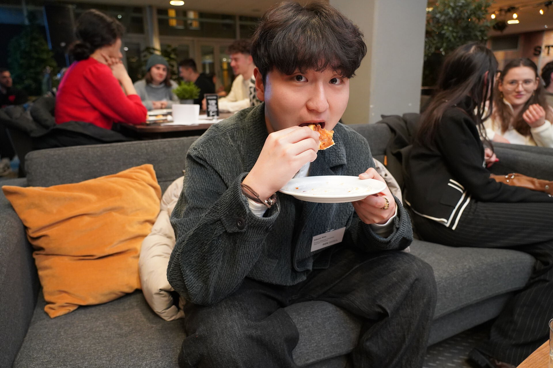Portrait of Kimbum Kim sitting in a sofa and eating pizza