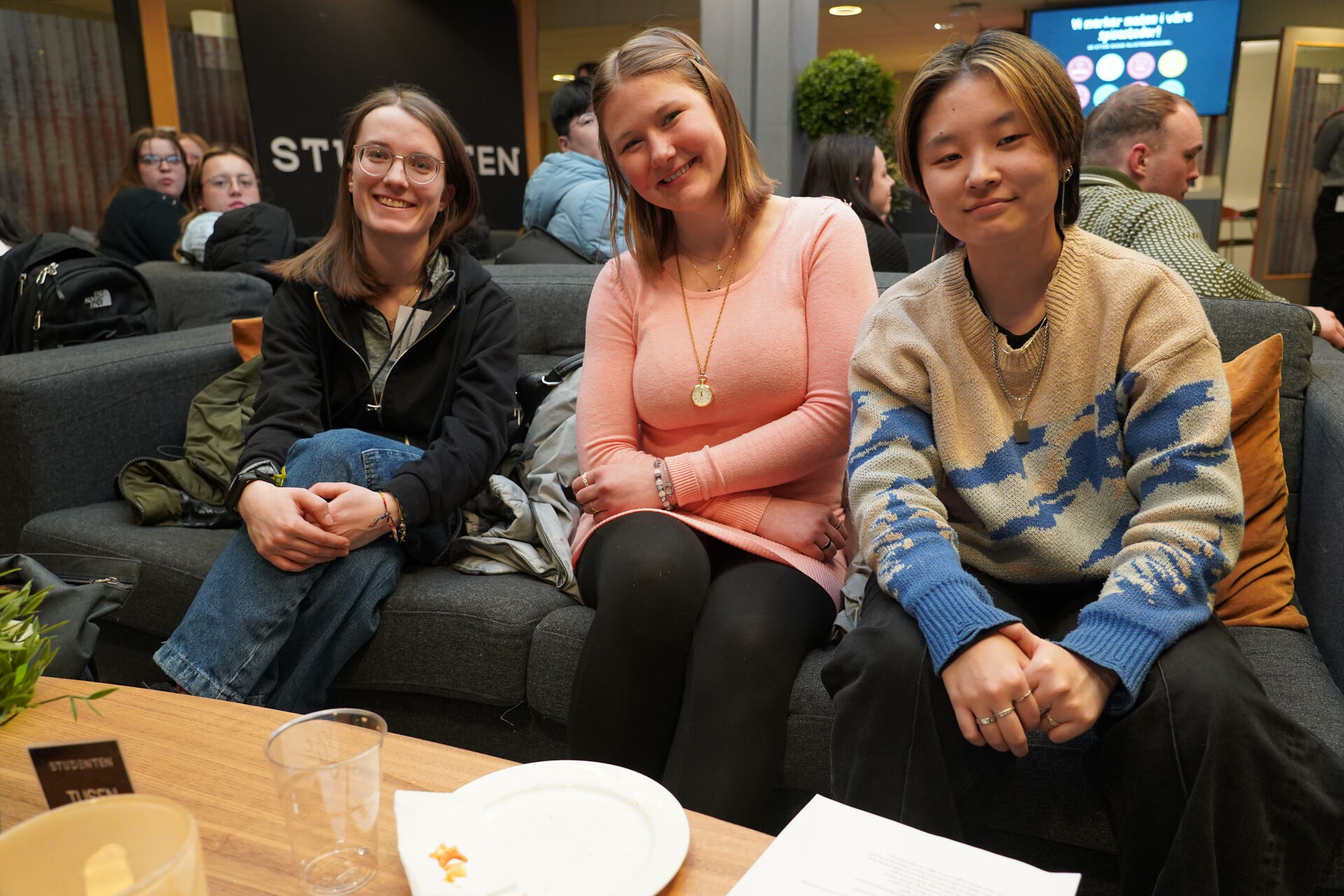 Finja, Daniela and Sigrid are sitting in a sofa and smiling at Studenten