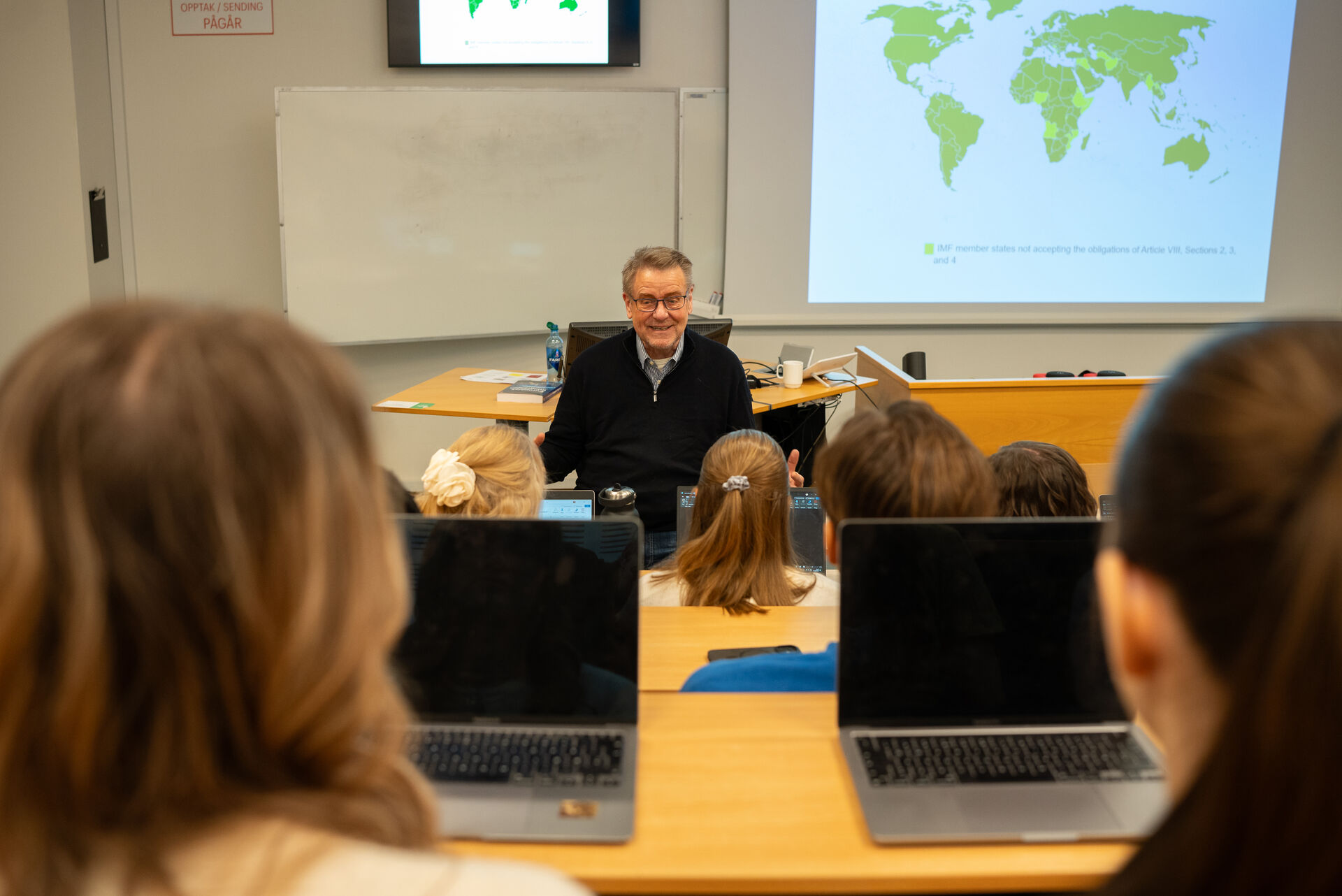 A lecturer in front of a world map