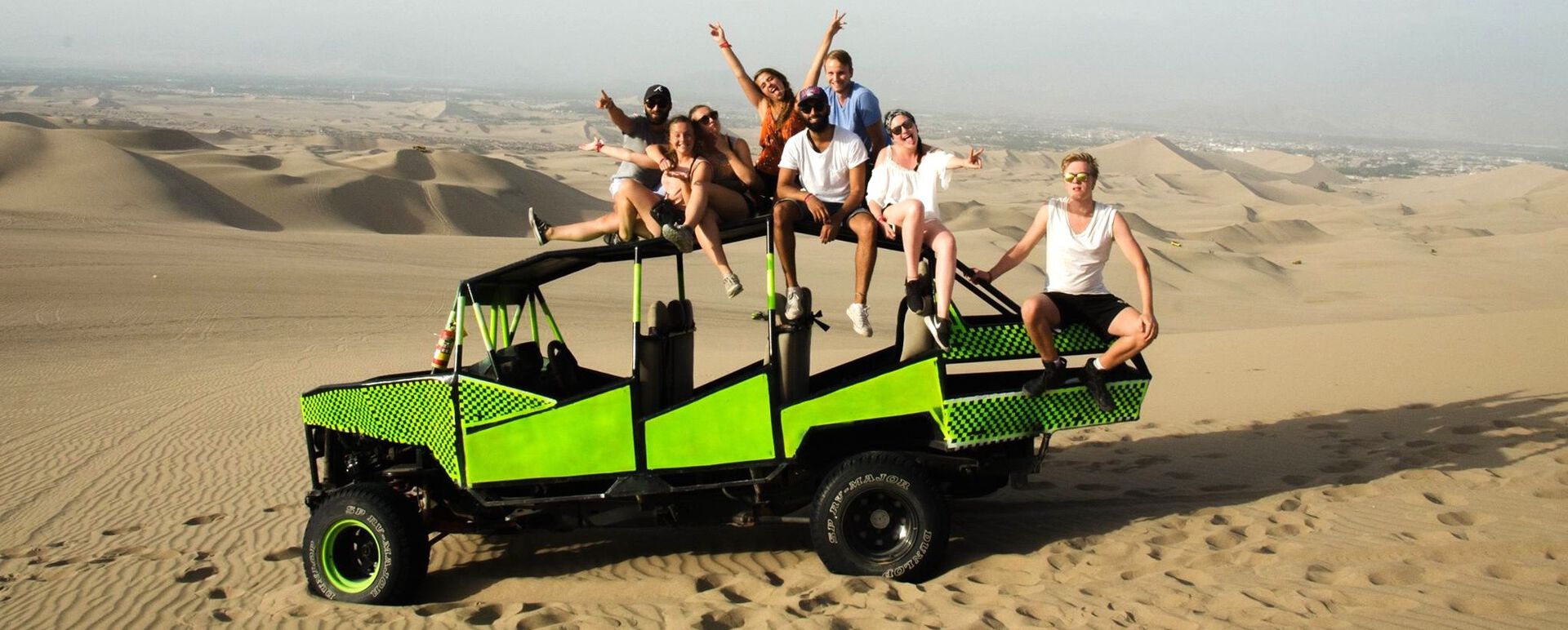 8 students sitting on a vehicle in the desert.
