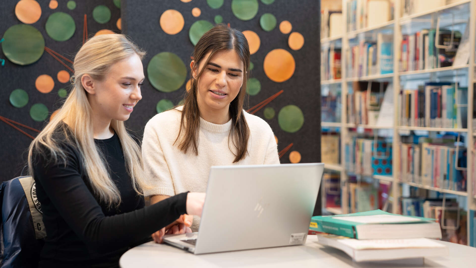 Two young women sitting and looking at a laptop together