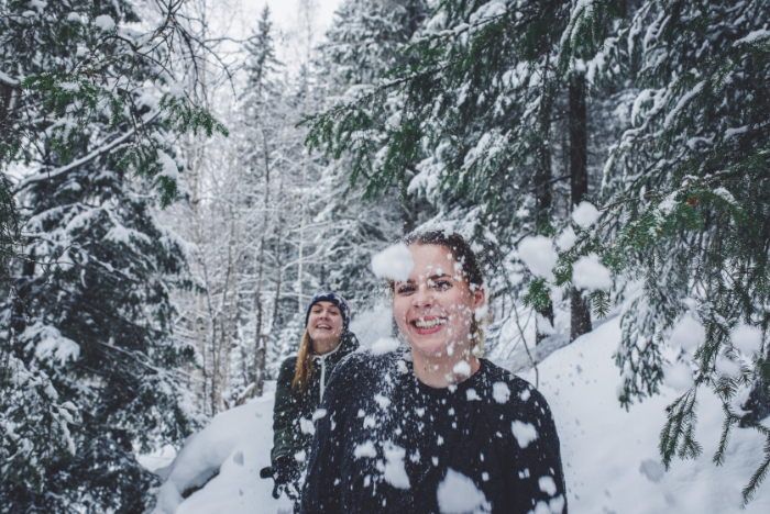 Female students having fun throwing snow in the snow covered forest