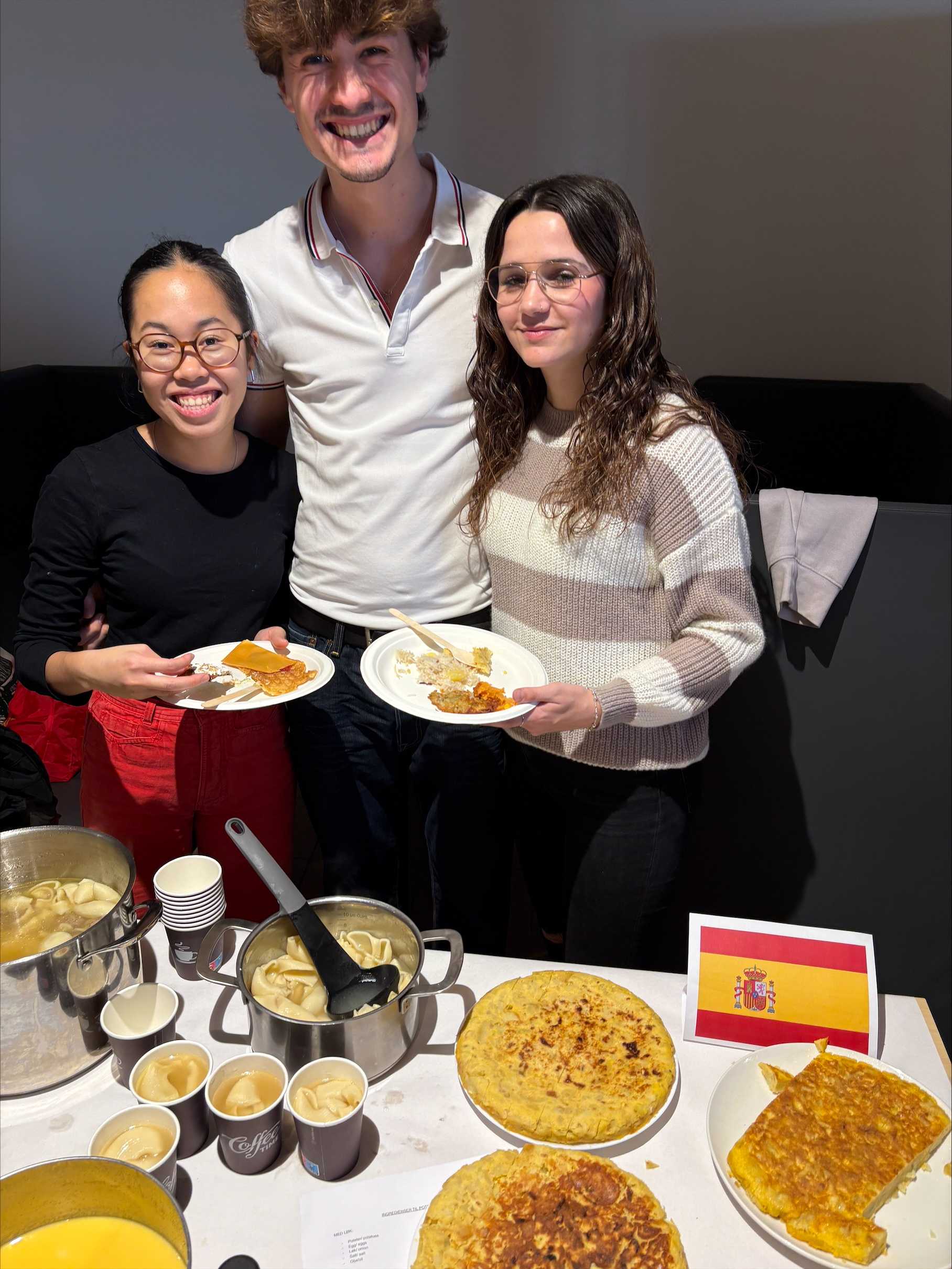 Three people are smiling and showing Spanish food