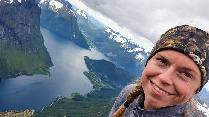Young lady stands on a mountain with a view to the fjords