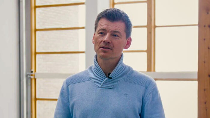 Man with light blue sweater in front of a window