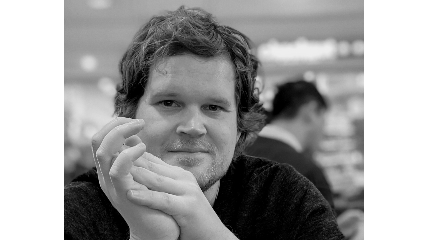 Portraitpicture in black and white in a room with som people blurry in the background
