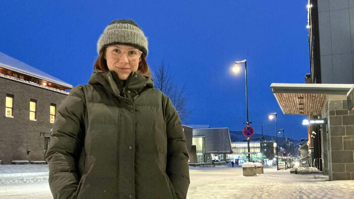 Woman with winterhat and winterjacket in downtown Lillehammer at night