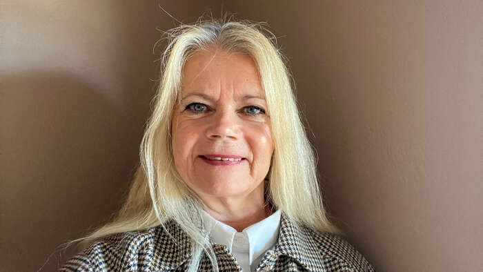 Woman with blonde hair against a brown wall