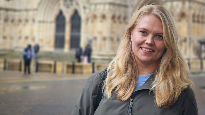 Woman with blonde hair in front of a old stonechurch