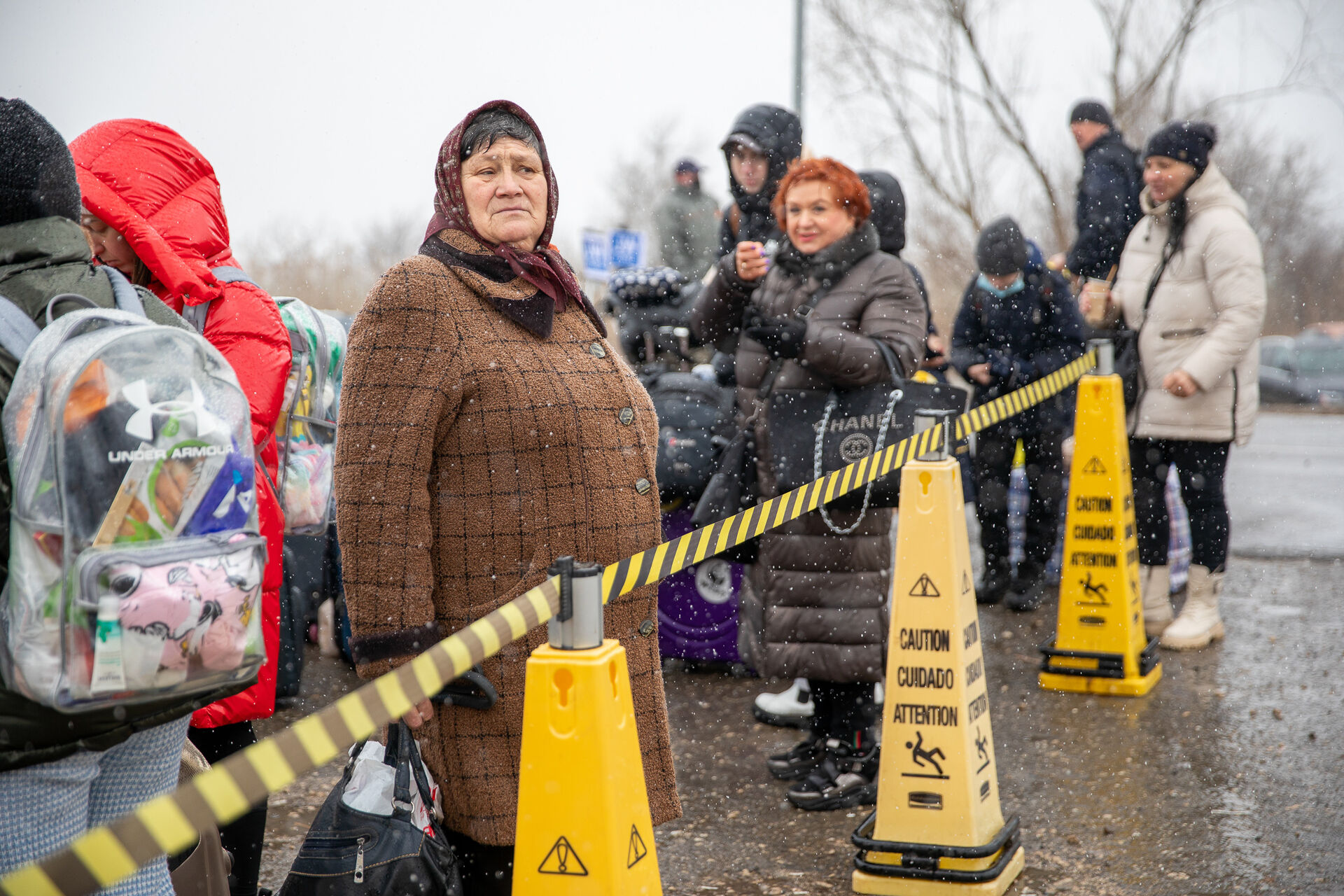 An elderly woman surrounded by other people at the border. 
