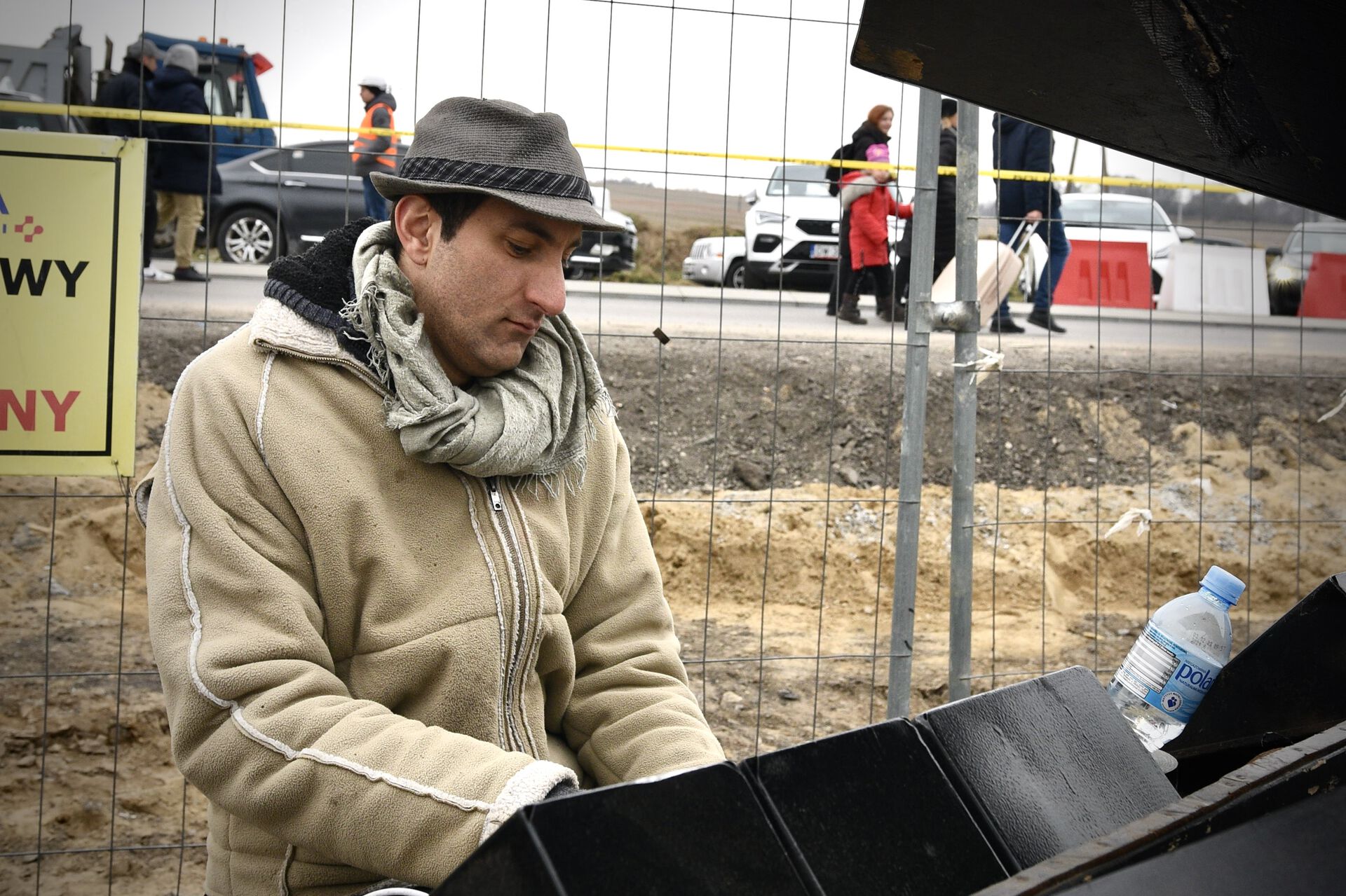 A man sits outdoors and plays piano. 