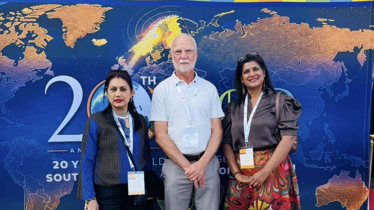 Three persons in front of a world map