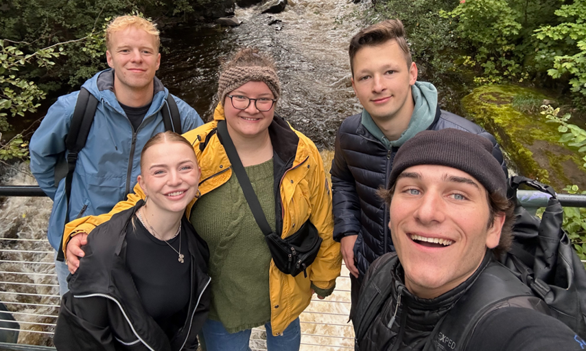 Student standing in front of a waterfall and smiling