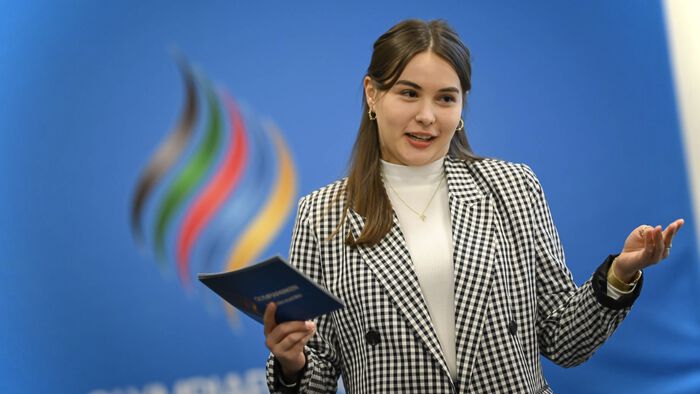 Elisa presenting during her internship at Olympiaparken, with the logo in the back.