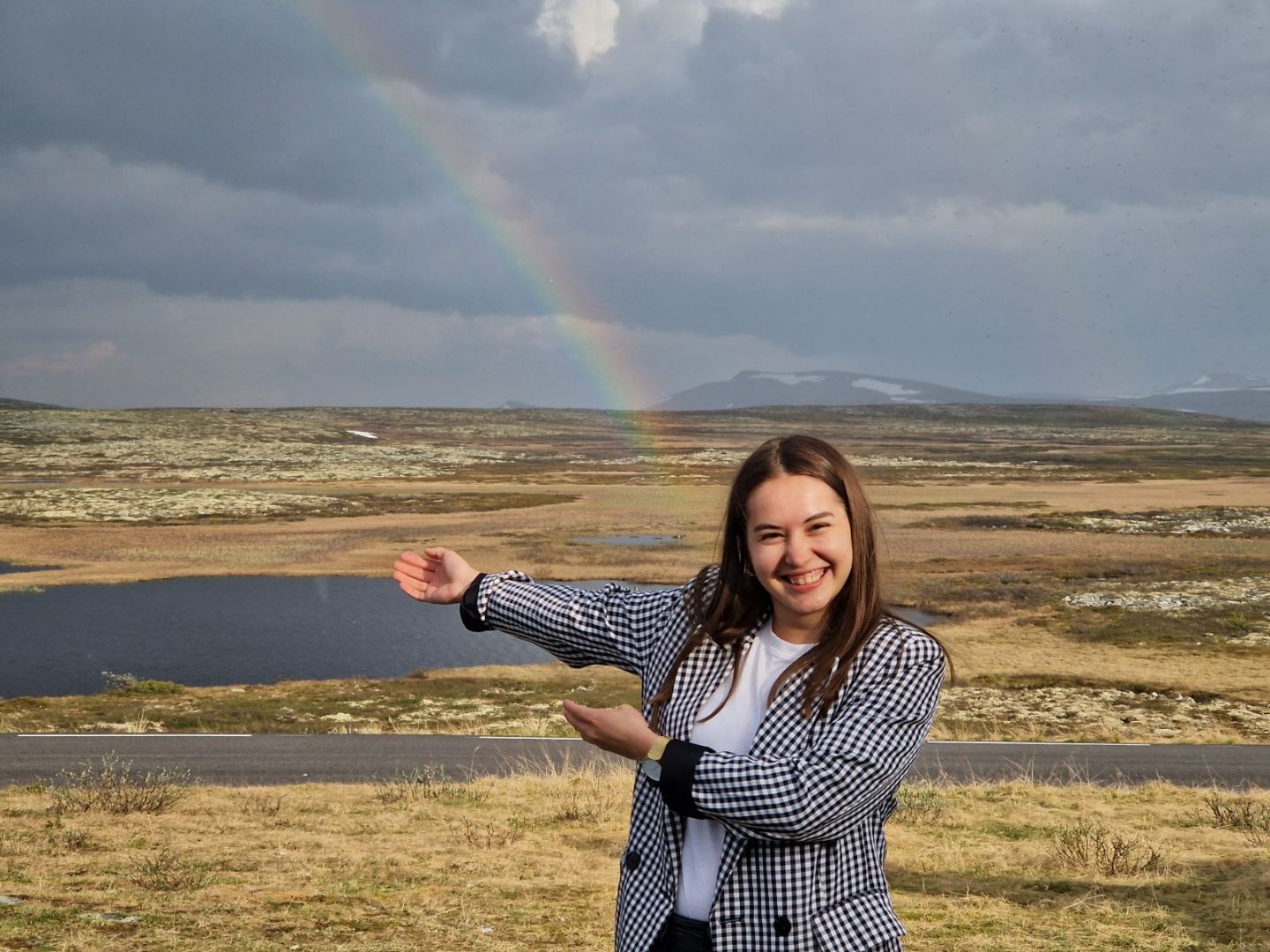 Exchange student posing in front of the end of the rainbow on top of flat mountain range