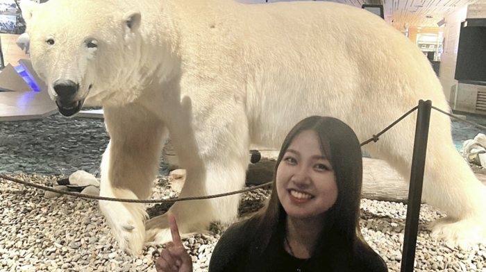 Eriko standing in front of an exhibition and pointing at a preserved white polar bear