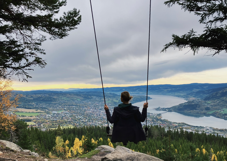 Kristine playing on the swing on top of the mountain Balbergkampen, with a view of Lillehammer in the autumn.