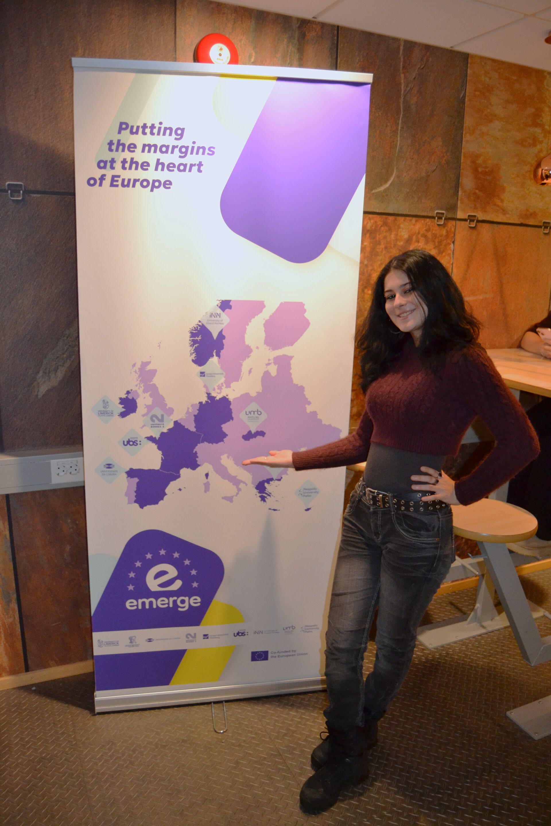 Timea in front of an EMERGE poster