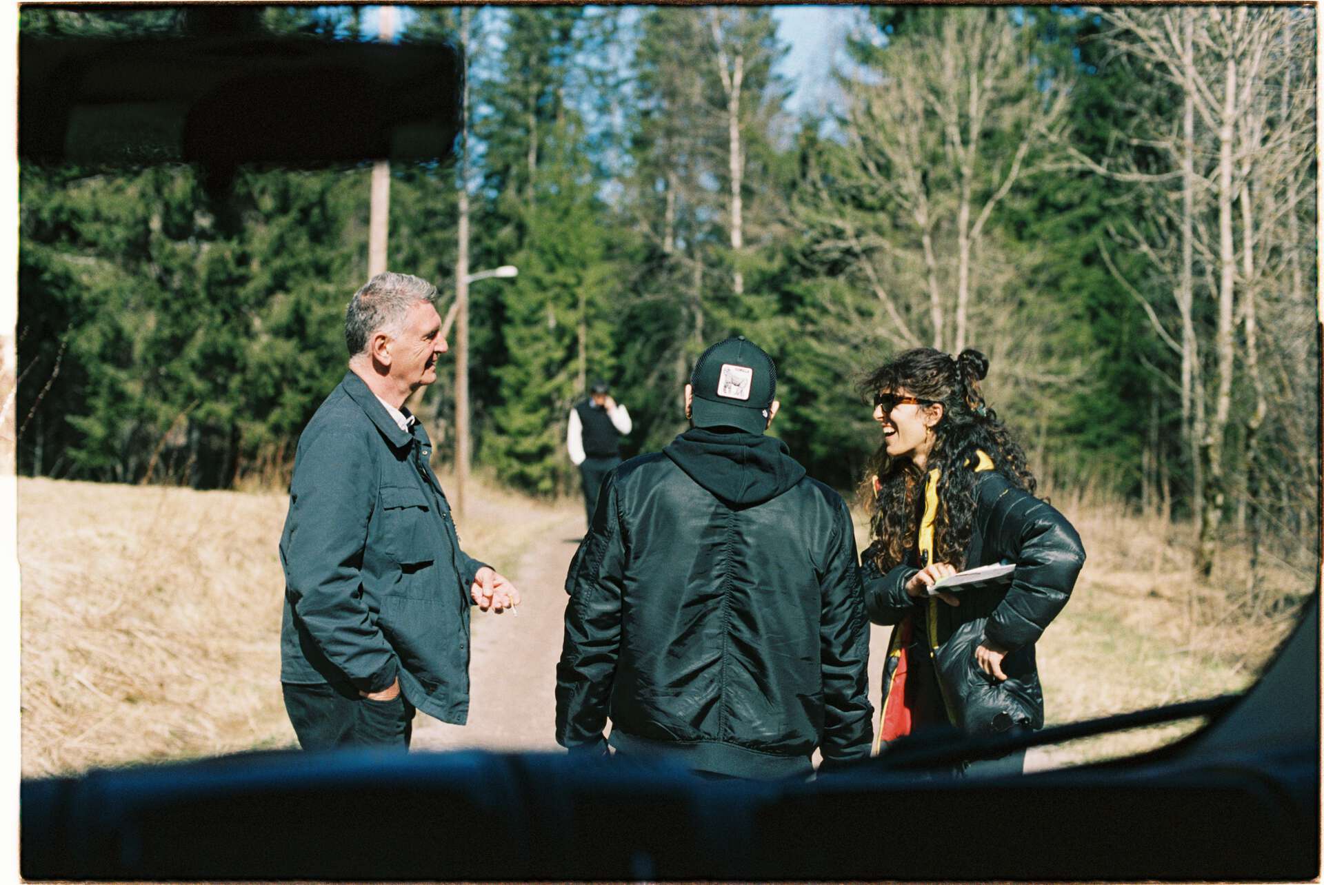 Gjennom bilvindu ser vi et filmcrew i skogen
