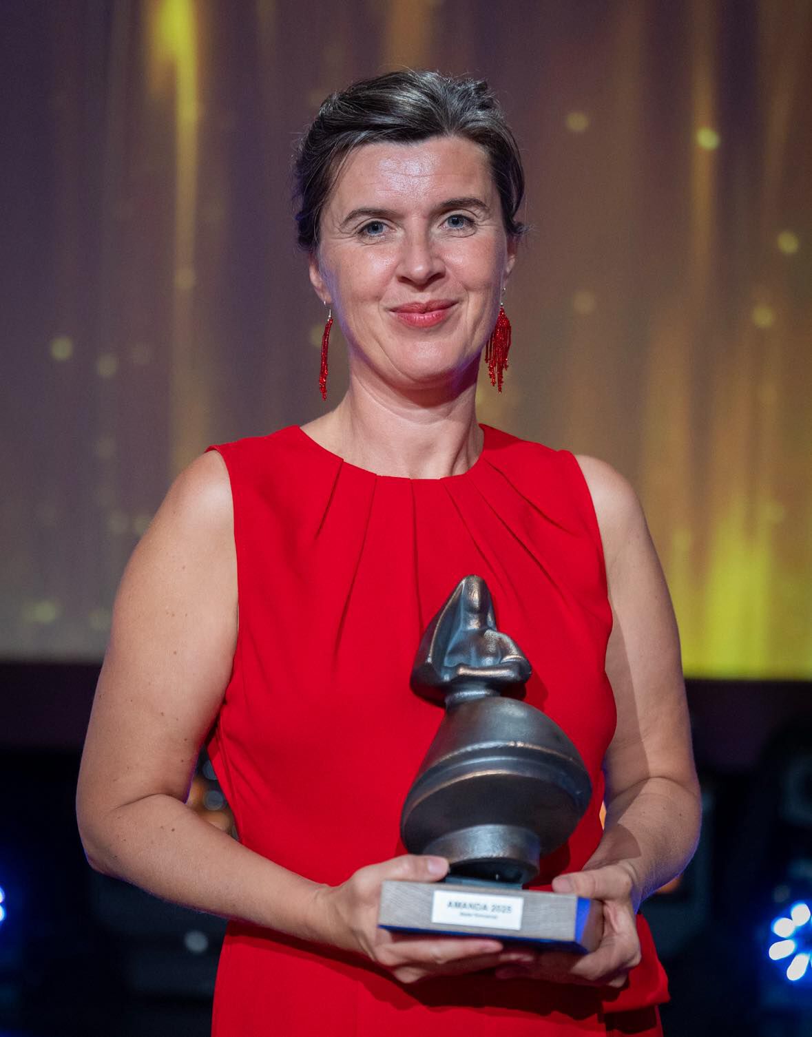 En strålende Lilja Ingolfsdottir i rød kjole holder Amanda-statuetten i hendene.