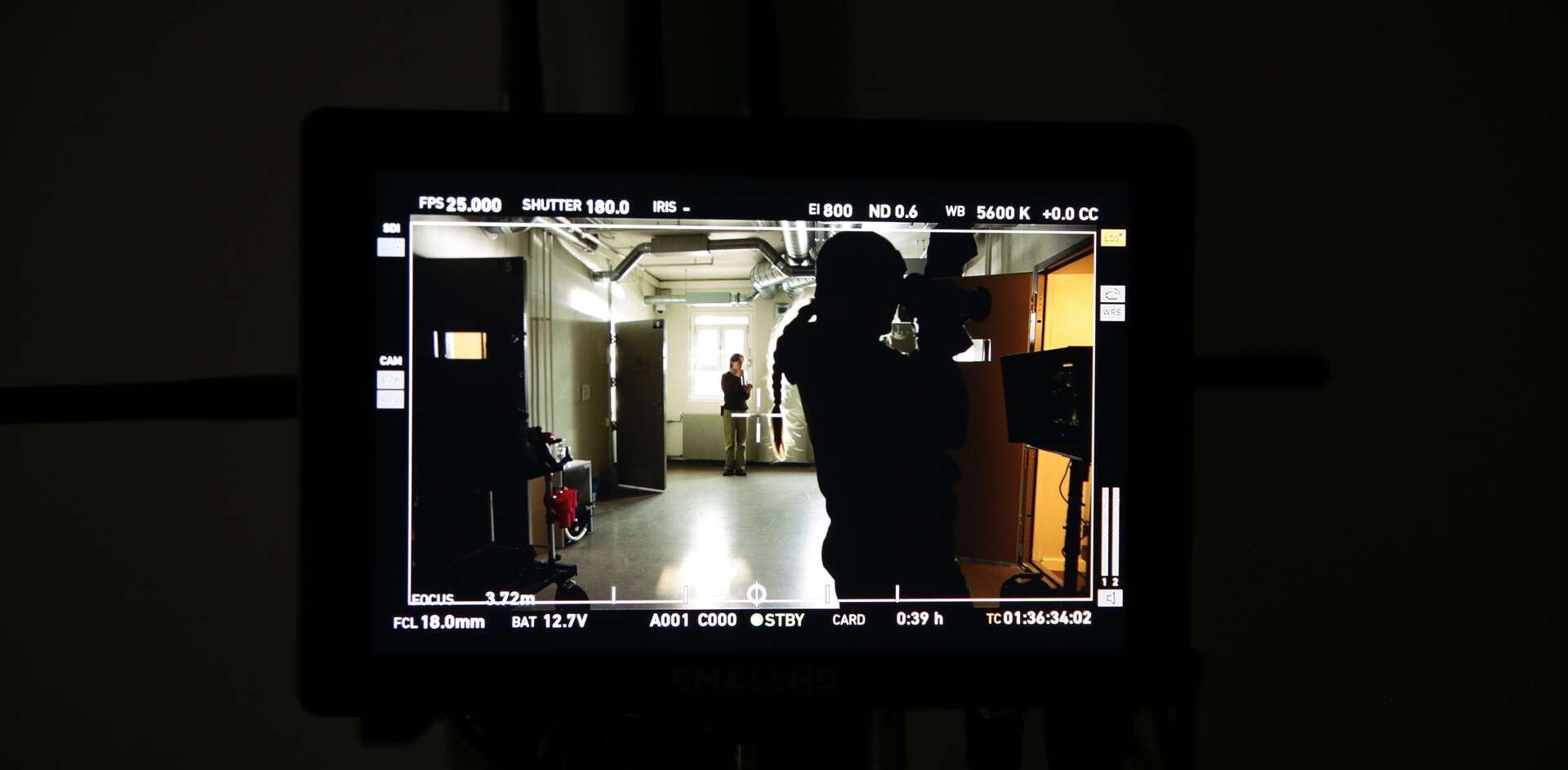 Gjennom en filmmonitor ser vi en person som filmer i en fengselsgang i