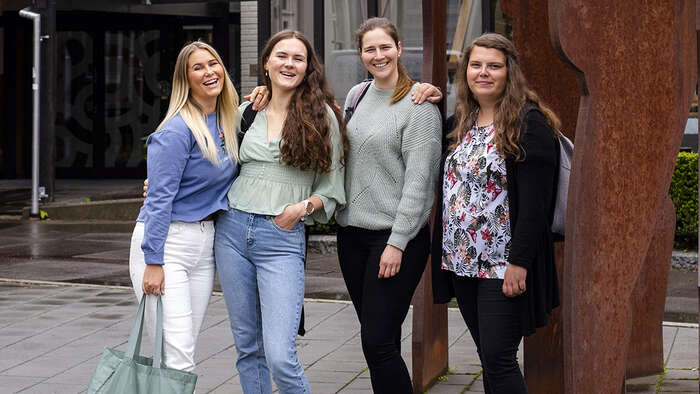 Fire jenter foran en bygning. 