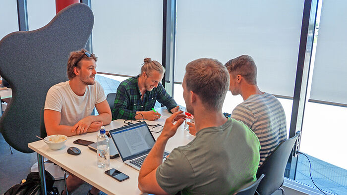 Fire mannlige studenter som jobber sammen på biblioteket i Terningen Arena. 