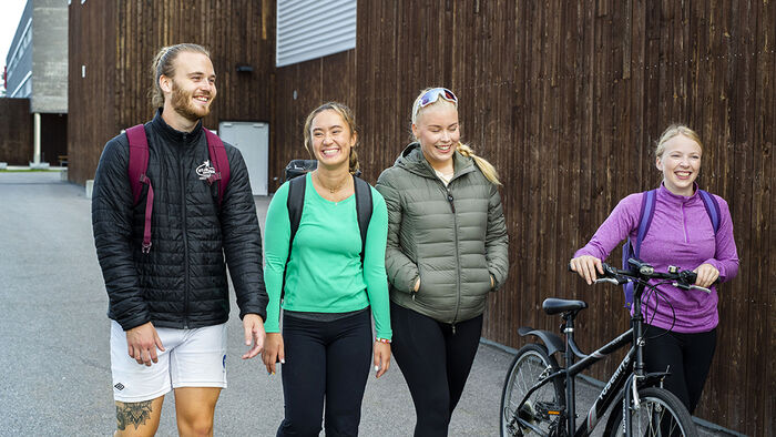 Smilende studenter som går sammen. 
