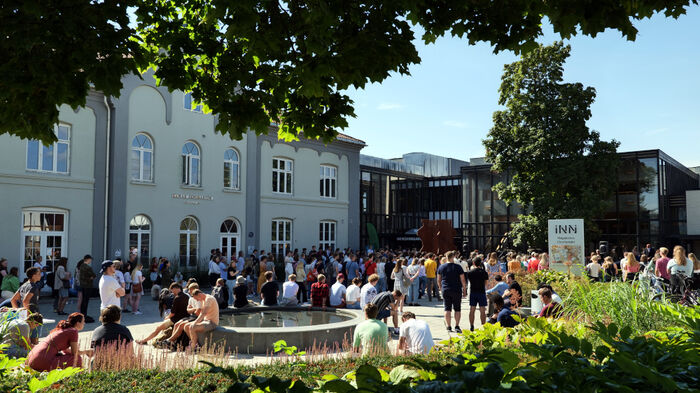 Utendørsfoto med mange studenter samlet utenfor høgskolens bygninger på Hamar