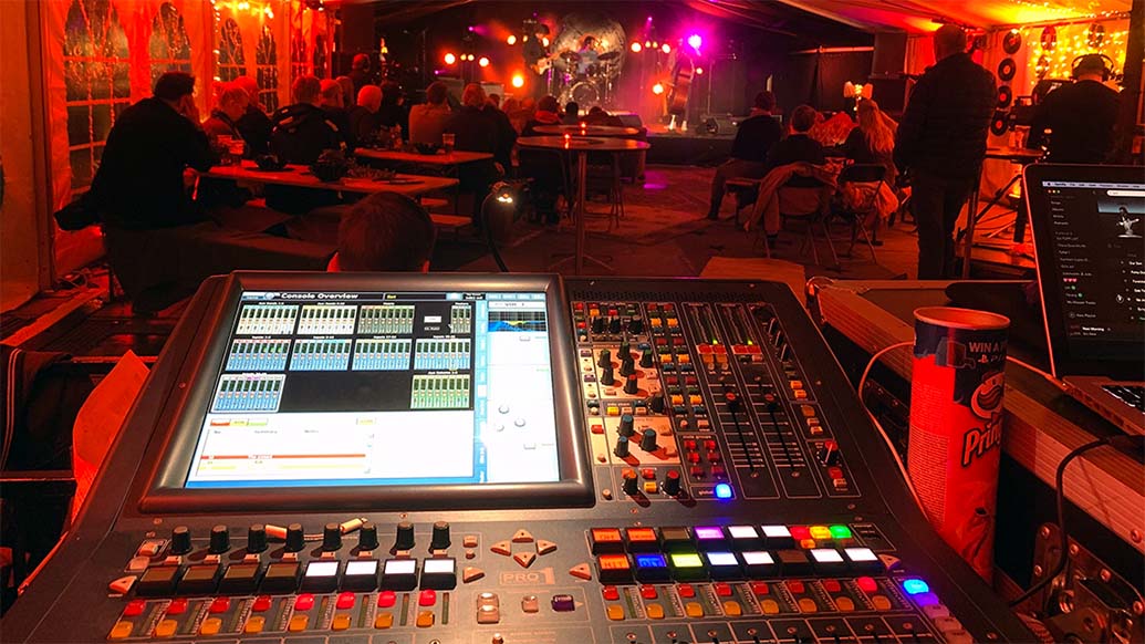 Miksebord i forgrunnen under en konsert. 