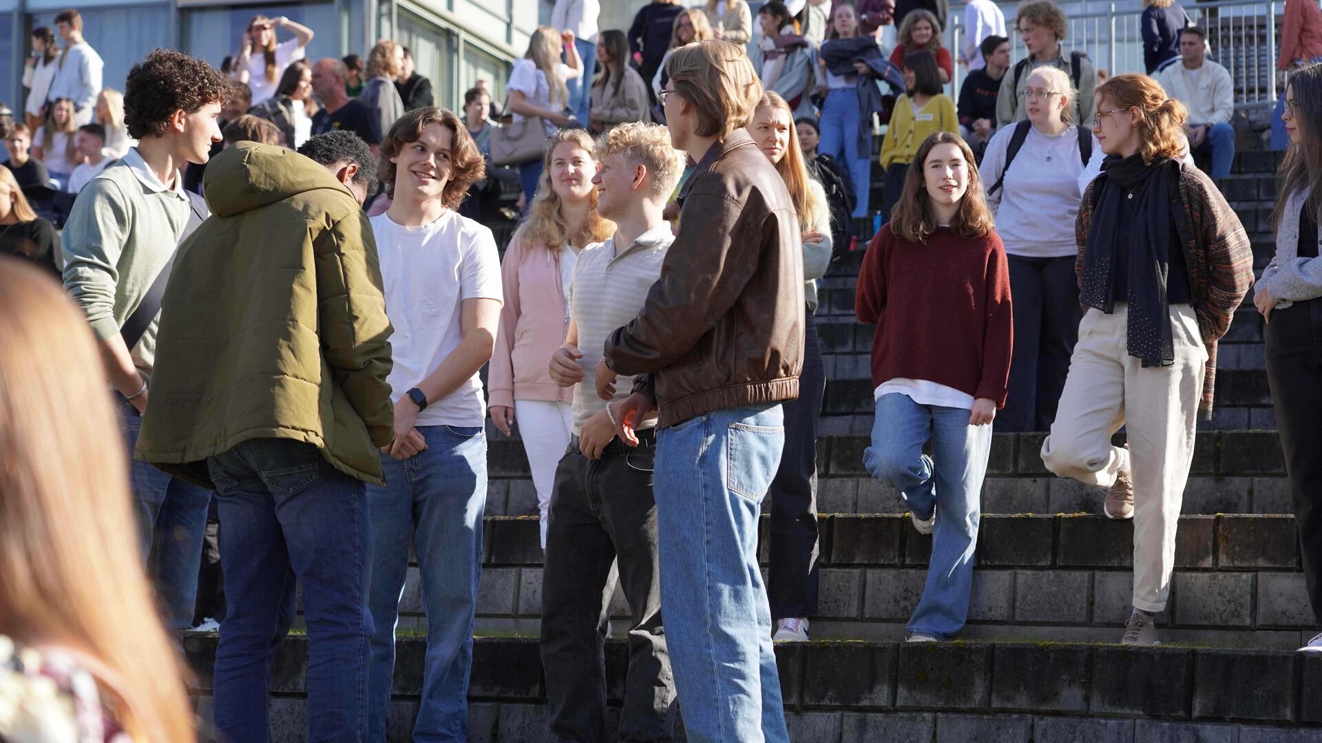 Studenter har samlet seg i amfiet, noen står i grupper og prater.