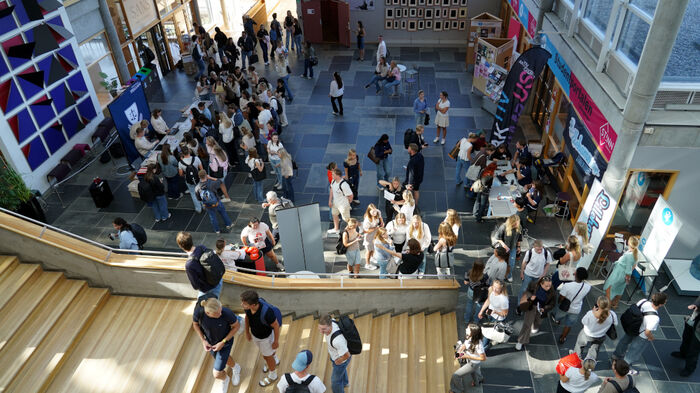 Oversiktsbilde over en trapp i forkant av bildet med flere personer i, og et stort åpent areal i bakgrunnen med mange studenter